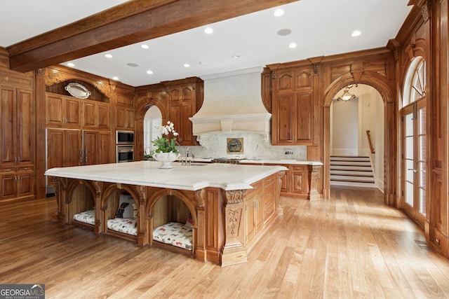 0 Winterthur, Sandy Springs, GA 30328 - kitchen with open shelves, custom range hood, appliances with stainless steel finishes, arched walkways, and light wood finished floors