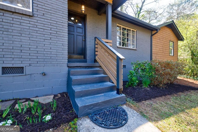 view of exterior entry featuring brick siding and crawl space