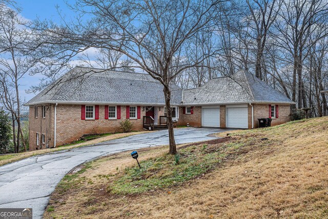 ranch-style house featuring driveway, brick siding, an attached garage, and a front yard