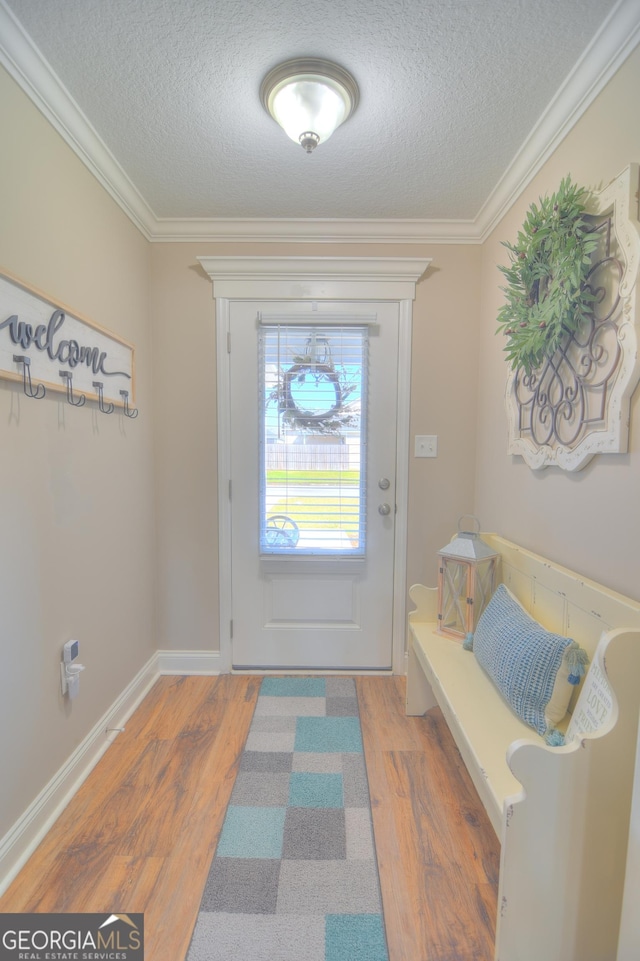 doorway featuring a textured ceiling, crown molding, baseboards, and wood finished floors