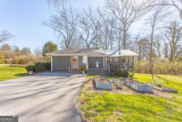 view of front of property with driveway, a front yard, and a vegetable garden