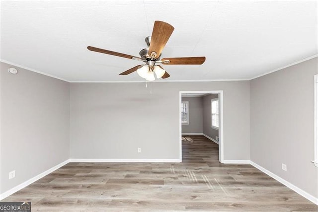 spare room with a ceiling fan, crown molding, baseboards, and wood finished floors