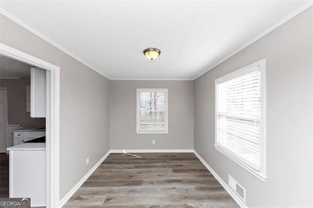 unfurnished dining area featuring crown molding, wood finished floors, visible vents, and baseboards