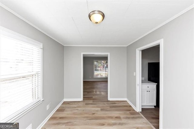 interior space with baseboards, light wood-style floors, and ornamental molding