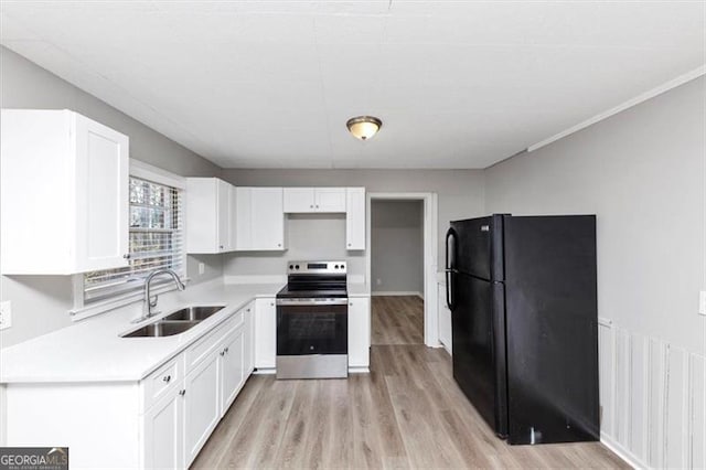 kitchen with a sink, white cabinetry, electric stove, and freestanding refrigerator