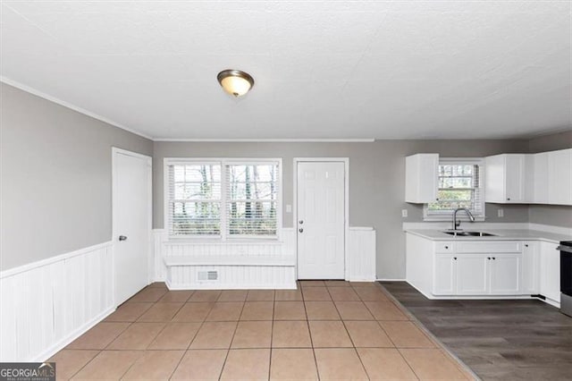 kitchen with visible vents, a sink, light countertops, white cabinets, and wainscoting