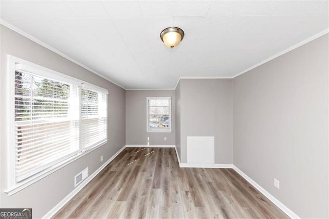 empty room featuring visible vents, baseboards, wood finished floors, and crown molding