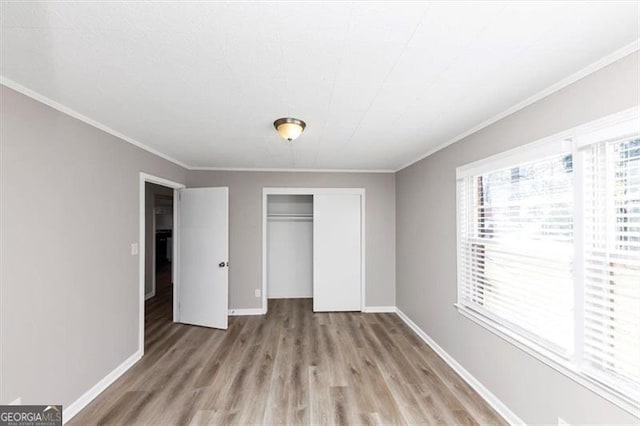 unfurnished bedroom with crown molding, baseboards, a closet, and light wood-type flooring