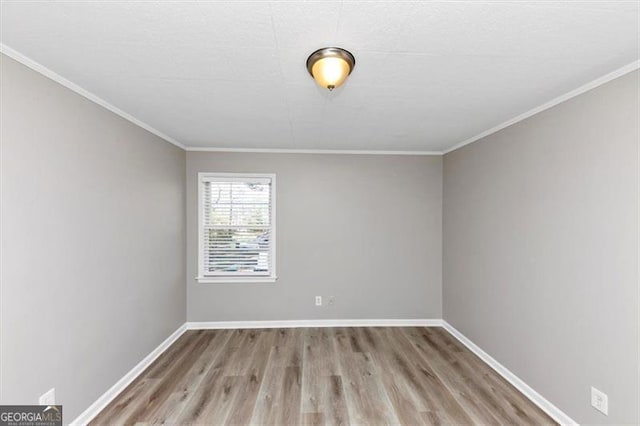 empty room with baseboards, wood finished floors, and crown molding