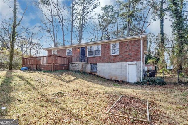 back of house with brick siding, a wooden deck, a yard, and a vegetable garden