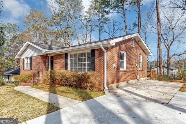 ranch-style house with concrete driveway, brick siding, and a front yard