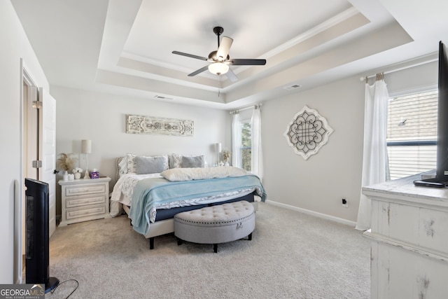 bedroom featuring visible vents, light carpet, a ceiling fan, a tray ceiling, and baseboards