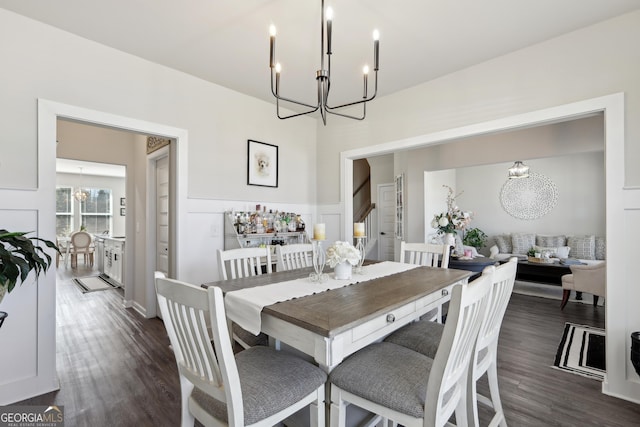 dining area with a chandelier, dark wood-style flooring, and a decorative wall