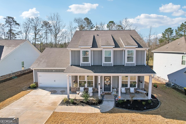 traditional home with central air condition unit, board and batten siding, covered porch, concrete driveway, and an attached garage