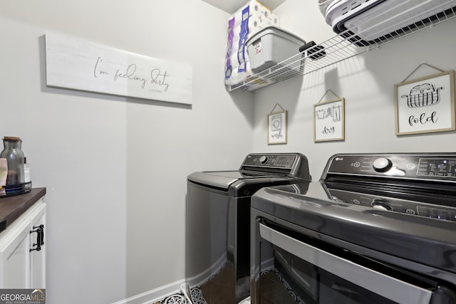 clothes washing area featuring washer and dryer, baseboards, and cabinet space