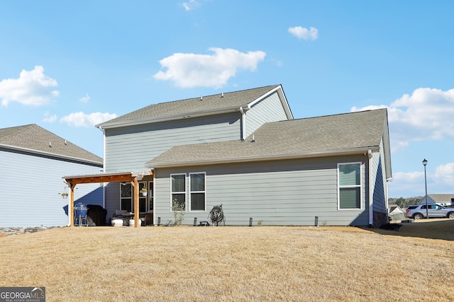 back of house with a yard, a pergola, and roof with shingles