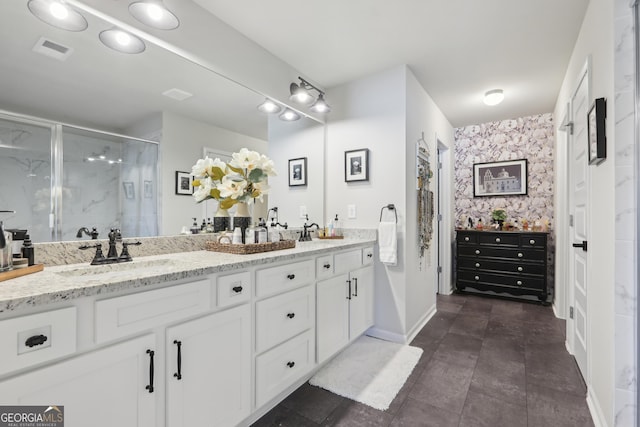 full bathroom featuring visible vents, a sink, a shower stall, wallpapered walls, and double vanity