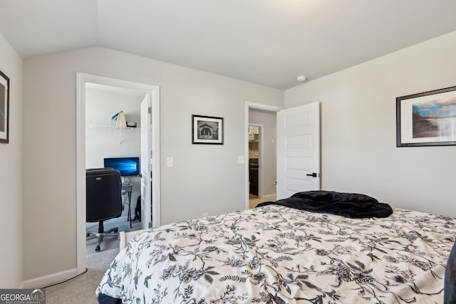 bedroom with a walk in closet, baseboards, lofted ceiling, carpet flooring, and a closet