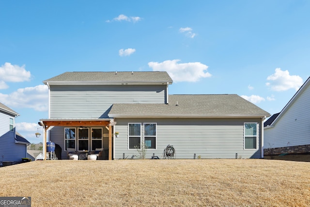 back of house featuring a lawn and a shingled roof