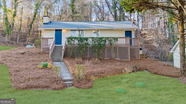 view of front of home featuring a wooden deck, a front lawn, and a chimney