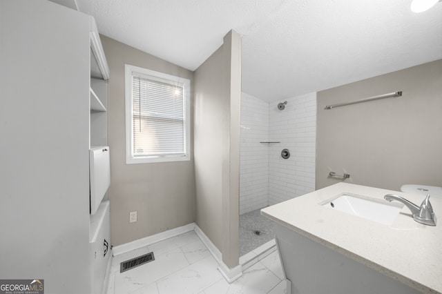 full bath with visible vents, baseboards, a tile shower, marble finish floor, and a textured ceiling
