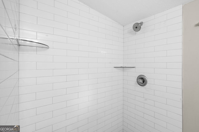 full bath featuring vaulted ceiling, a tile shower, and a textured ceiling