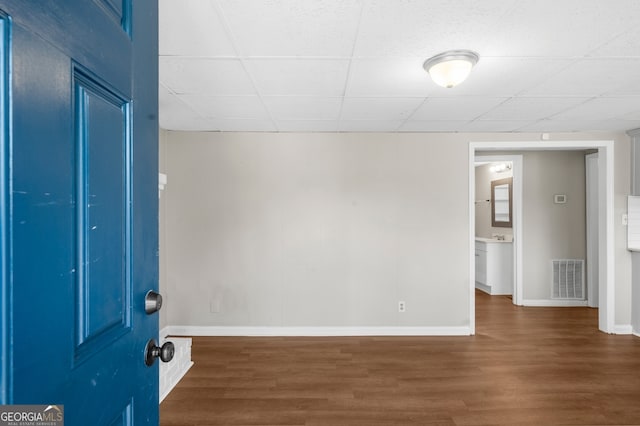 interior space with visible vents, a paneled ceiling, baseboards, and wood finished floors