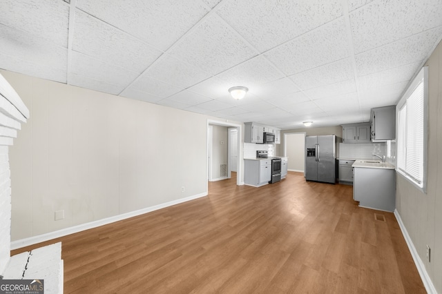 unfurnished living room with a sink, baseboards, and wood finished floors