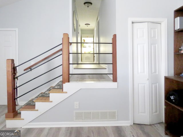 stairs featuring wood finished floors, visible vents, and baseboards