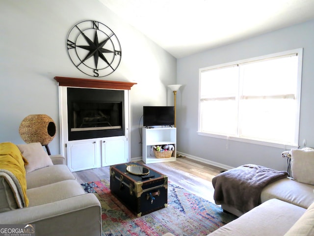 living room with vaulted ceiling, baseboards, and wood finished floors