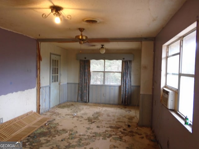 empty room with visible vents, wainscoting, cooling unit, and ceiling fan