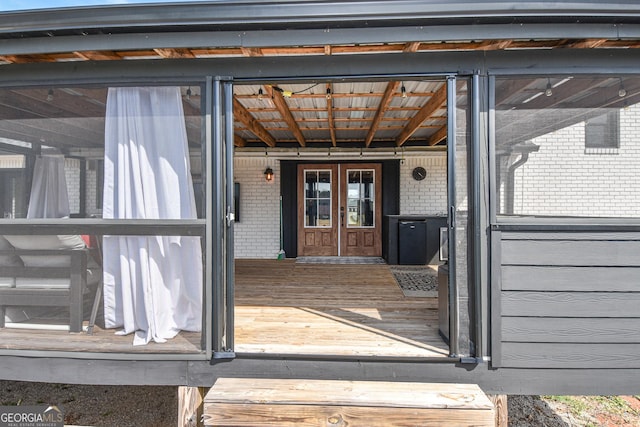 view of exterior entry featuring french doors and brick siding