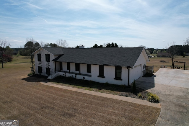 view of front of property featuring concrete driveway, a front yard, and roof with shingles