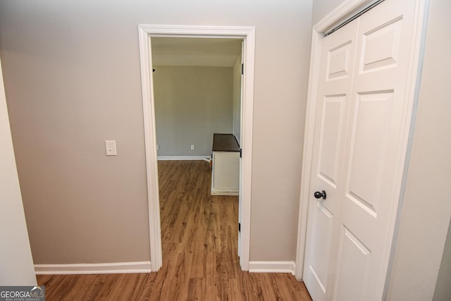 hallway featuring baseboards and wood finished floors