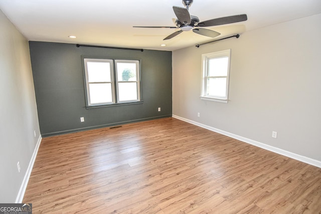 empty room with baseboards, wood finished floors, a healthy amount of sunlight, and ceiling fan