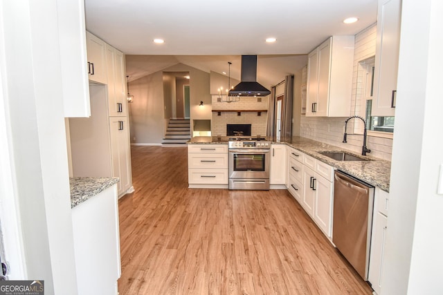 kitchen with light wood-style flooring, a sink, open floor plan, ventilation hood, and appliances with stainless steel finishes