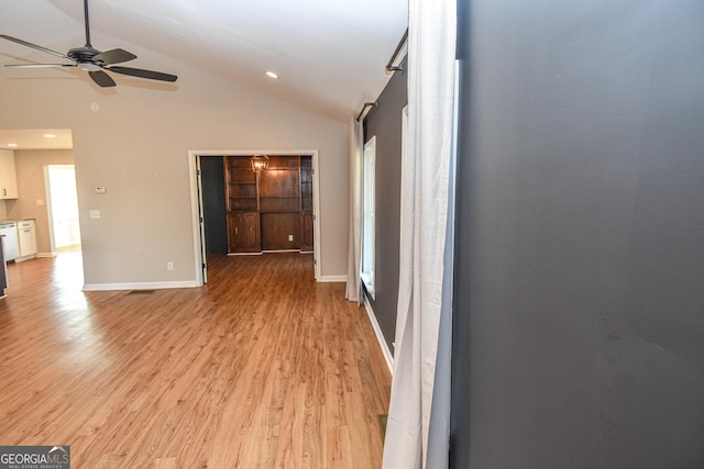 interior space featuring a ceiling fan, visible vents, baseboards, high vaulted ceiling, and light wood-type flooring