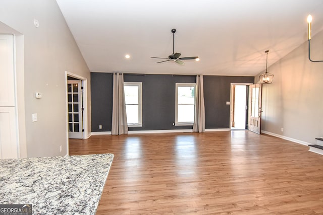 unfurnished living room featuring vaulted ceiling, light wood-style flooring, a ceiling fan, and baseboards