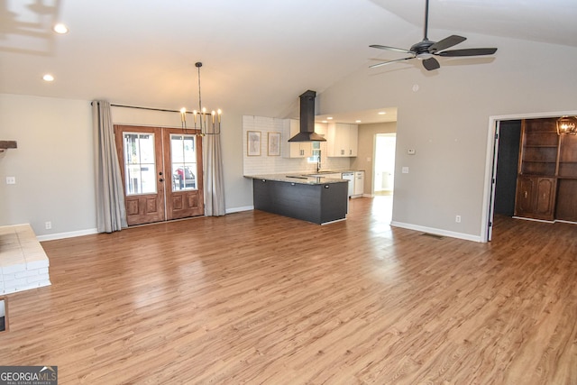 unfurnished living room with visible vents, light wood-style flooring, ceiling fan with notable chandelier, and baseboards