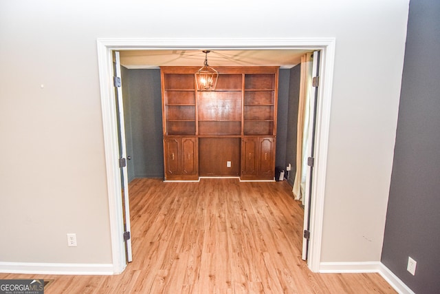 interior space featuring baseboards, an inviting chandelier, and light wood-style flooring