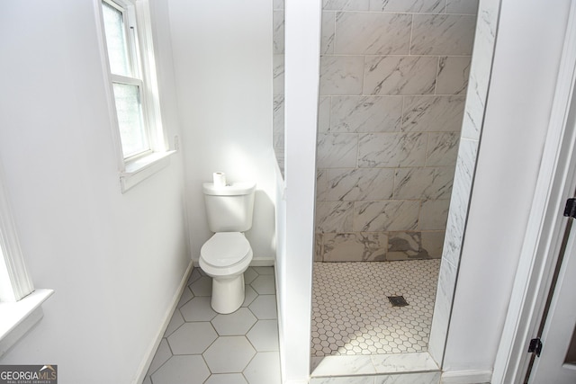 bathroom featuring a stall shower, toilet, and baseboards