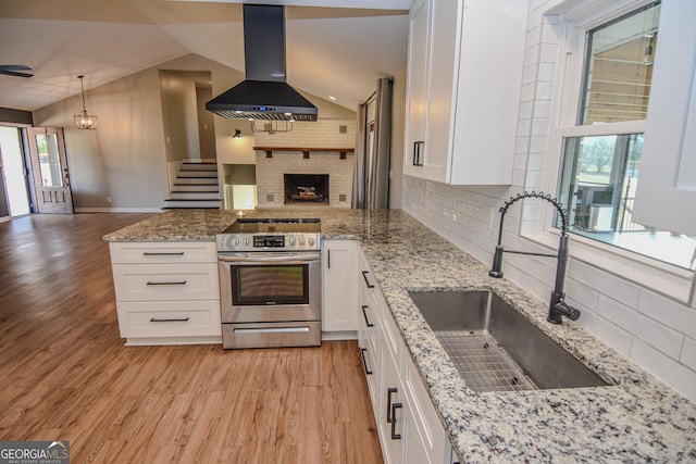 kitchen featuring stainless steel range with electric stovetop, a sink, open floor plan, a peninsula, and extractor fan