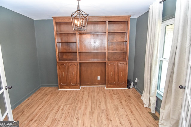 interior space with an inviting chandelier, baseboards, and light wood-type flooring