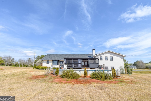 back of property with a yard, an outdoor pool, a sunroom, and a chimney