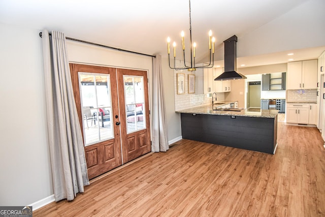 kitchen with a chandelier, light wood-style flooring, french doors, island range hood, and a sink