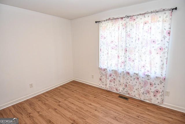 empty room with visible vents, baseboards, and wood finished floors