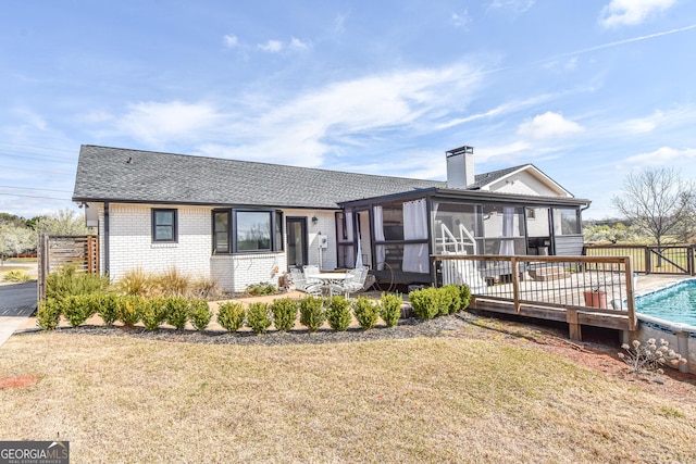 ranch-style house featuring a front yard, a fenced in pool, a sunroom, a chimney, and brick siding