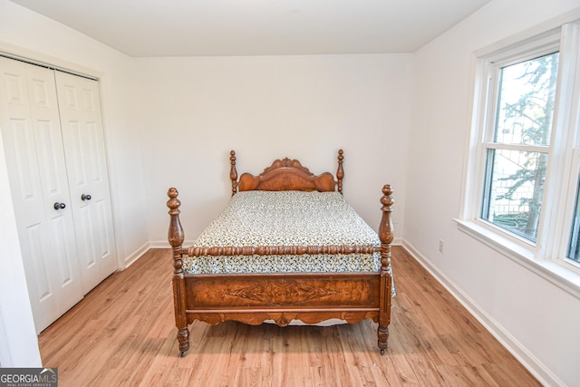 bedroom featuring a closet, multiple windows, baseboards, and light wood-style floors