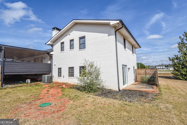 rear view of house with a patio, central AC unit, a lawn, and a chimney