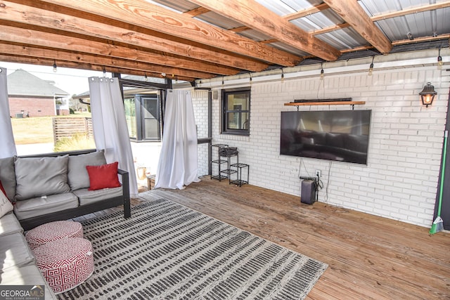 living area featuring wood finished floors and brick wall